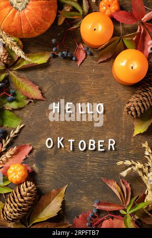 Hello oktober text, autumn season. Greeting card, fallen leaves, pumpkins and cones on a wooden board. Autumn natural background. View from above. Stock Photo