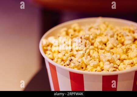Popcorn box close up Movie theatre popcorn background. Entertainment concept. Cinema trendy. Movie snack. Salted popcorn in bucket. Fast food. Stock Photo