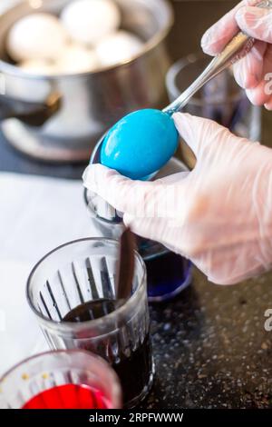 A woman paints eggs in liquid paint for the feast of the holy easter. Stock Photo