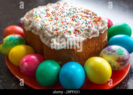 festive Easter cake, decorated with white fondant, painted multi-colored eggs lie around. Stock Photo