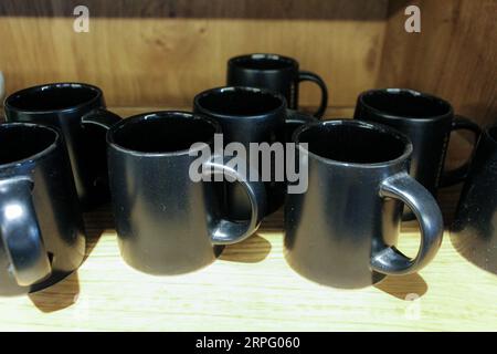 Expresso coffee black mugs on the wooding selling shelf. High-quality close-up photo Stock Photo