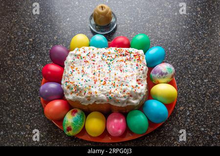 festive Easter cake and painted multi-colored eggs lying around, top view. Stock Photo