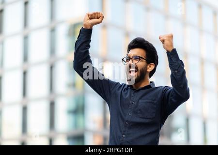 Successful young indian businessman celebrating success, business center background Stock Photo