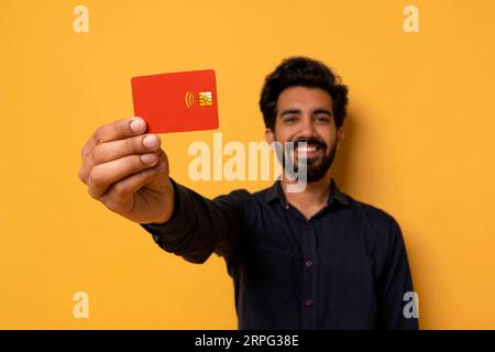 Smiling Young Indian Man Showing Credit Card At Camera Stock Photo