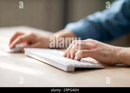 Unrecognizable Man Typing On Computer Keyboard And Using Wireless Mouse Stock Photo