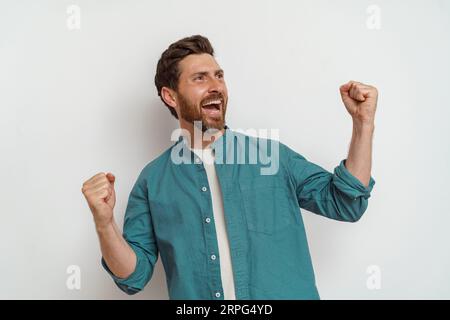 Surprised and smiling man standing on white background and screaming with rise arms Stock Photo