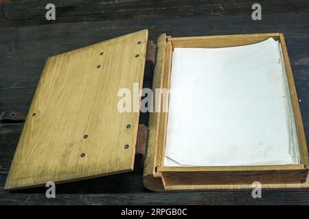 old log book in a wooden case with clasps on a black tabletop, open Stock Photo
