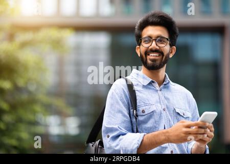 Cheerful eastern millennial man IT manager using cell phone Stock Photo