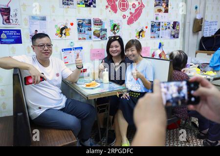 191012 -- HONG KONG, Oct. 12, 2019 -- Kate Lee 3rd L poses for a photo with customers at her tea restaurant in Kowloon, south China s Hong Kong, Oct. 10, 2019. Nestling in the labyrinthine seafood market of the quiet Lei Yue Mun fishing village in Hong Kong, a snug little tea restaurant has unexpectedly become a beacon of courage for ordinary Hong Kong people seeking peace amid the recent chaos. After she posted pictures backing up Hong Kong police against some radical protesters at the end of June, Kate Lee, the owner of the tea restaurant, found her conscience took a heavy toll on her family Stock Photo