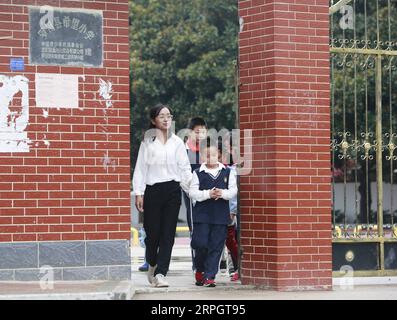 191022 -- LUOTIAN, Oct. 22, 2019 -- Fang Rong walks students home in Luotian County, central China s Hubei Province, Oct. 11, 2019. Fang Rong, 29, is the headmaster of Hope primary school of Luotian County, her alma mater. Born in a poverty-stricken region, Fang Rong was a left-behind girl. Thanks to the Hope Project and people s aids, she succeeded in graduating from a secondary normal school. To help more children and repay people s kindness, she decided to be a teacher at her alma mater. In spite of the austere way of life, Fang shouldered her responsibility from various aspects. Her studen Stock Photo