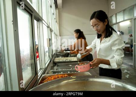 191022 -- LUOTIAN, Oct. 22, 2019 -- Fang Rong helps students with food in the canteen of Hope primary school in Luotian County, central China s Hubei Province, Oct. 11, 2019. Fang Rong, 29, is the headmaster of Hope primary school of Luotian County, her alma mater. Born in a poverty-stricken region, Fang Rong was a left-behind girl. Thanks to the Hope Project and people s aids, she succeeded in graduating from a secondary normal school. To help more children and repay people s kindness, she decided to be a teacher at her alma mater. In spite of the austere way of life, Fang shouldered her resp Stock Photo