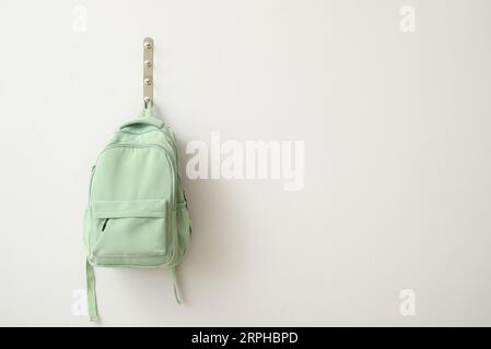 School backpack hanging on light wall Stock Photo