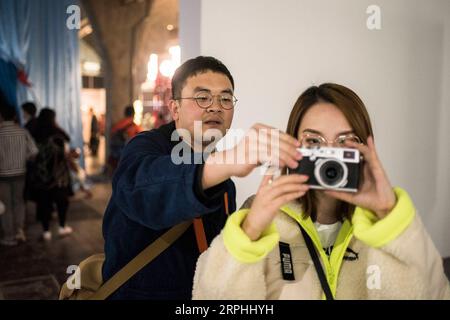 191109 -- BEIJING, Nov. 9, 2019 -- Liu Gaochao L teaches a friend how to operate a camera at the 798 art zone in Beijing, capital of China, Nov. 9, 2019. It s been more than five years since Liu Gaochao embraced a career in film developing. On top of a high-rise mansion next to Liufang Station of Beijing Subway Line 13, Liu runs a studio, New Wave Film Lab, which also provides him a place to live. In 2012, Liu left his hometown in central China s Henan Province and headed for Beijing in pursuit of better opportunities. After he settled down in the capital city, he came across film photography Stock Photo