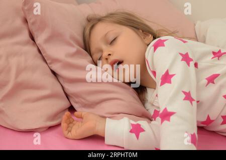 Little girl snoring while sleeping in bed Stock Photo