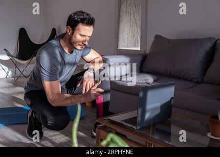 Latino fitness instructor teaching online in front of his laptop. Work at home - online training with client. Stock Photo