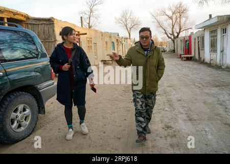191128 -- YUTIAN, Nov. 28, 2019 -- Kurbanhan Matrozi L discusses with a tour guide on the arrangement of visitors in Darya Boyi Township, Yutian County of northwest China s Xinjiang Uygur Autonomous Region, Nov. 13, 2019. Darya Boyi Township is at the heart of the Taklimakan desert. People here live in poor conditions due to the natural environment. However, the place has become a hot destination in recent years with adventurous tourism getting popular. The 24-year-old Kurbanhan Matrozi, who is born in the township, is the first college student of her hometown. She gave up her job in the city Stock Photo