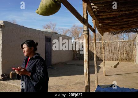 191128 -- YUTIAN, Nov. 28, 2019 -- Kurbanhan Matrozi waits for the call of a tour guide at home in Darya Boyi Township, Yutian County of northwest China s Xinjiang Uygur Autonomous Region, Nov. 13, 2019. Darya Boyi Township is at the heart of the Taklimakan desert. People here live in poor conditions due to the natural environment. However, the place has become a hot destination in recent years with adventurous tourism getting popular. The 24-year-old Kurbanhan Matrozi, who is born in the township, is the first college student of her hometown. She gave up her job in the city and returned here Stock Photo