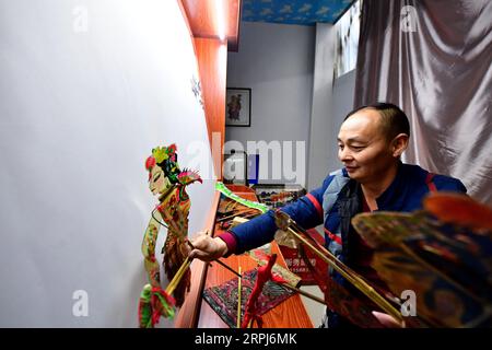191129 -- XINYANG, Nov. 29, 2019 -- Chen Yulun, an inheritor of the Luoshan Shadow Play, performs a shadow puppetry show to visitors at a shadow play inheritance and exchange base at Pengxin Township of Luoshan County, Xinyang City, central China s Henan Province, Nov. 27, 2019. Shadow play, also known as shadow puppetry, is a folk performing art originating in China. Luoshan Shadow Play, with a history of about 400 years, was listed as one of the national intangible cultural heritages in 2008. The puppets of Luoshan Shadow Play are made from cow leather with a series of complicated process. Stock Photo