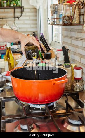 Chef pouring olive oil into pan on gas stove Stock Photo