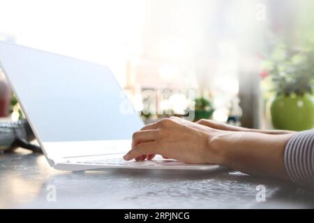 Modern office worker woman smiling brightly at home or office and working from home via internet online on laptop Stock Photo