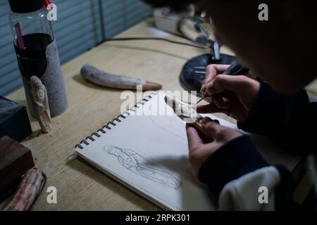 191226 -- BEIJING, Dec. 26, 2019 -- A student of Li Chunke carves according to sketches at a workshop of Beijing Light Industry Polytechnic College in Beijing, capital of China, Dec. 25, 2019. Tooth carving, originally meaning carving on ivory, is a traditional art in ancient China. It represented the peak of folk art in China during the Qing Dynasty 1644-1911 and became popular in the decorations for royal court. China has been intensifying its efforts in wildlife protection over the years. On Dec. 31, 2016, China declared it would enforce a complete stop to its domestic ivory trade within a Stock Photo