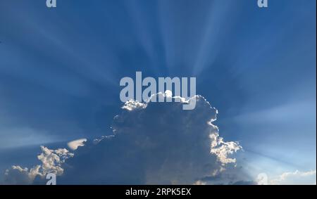 sunbeams shining through the clouds in the sky Stock Photo