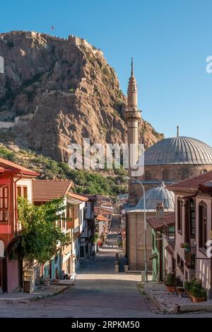 Traditional Turkish Ottoman houses in Afyonkarahisar Turkey. Afyon Castle on the rock and Mevlevihane Museum in front of it Stock Photo