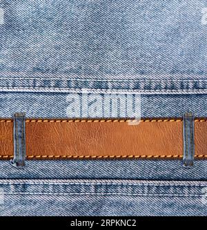 Blue denim background with leather belt. Horizontal or vertical backdrop with light blue color denim jeans fabric texture and brown leather strap. Moc Stock Photo