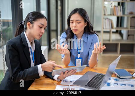 A professional and serious Asian businesswoman is having a serious discussion about a business financial investment project and using a digital tablet Stock Photo