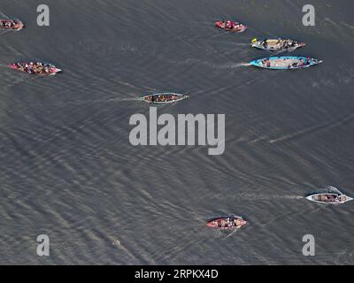 Gopalganj, Dhaka, Bangladesh. 5th Sep, 2023. Traditional boats compete with each other in the two-kilometer course during a boat race in Gopalganj, Bangladesh. The long vessels measure about 150 feet long and each is packed with up to 25 rowers. Each team of boatmen wears a single-colored t-shirt during the races. A drummer also sits on board each one during the event and songs are sung to help increase the rhythm and speed of the rowers along the river.  Credit: Z Credit: ZUMA Press, Inc./Alamy Live News Stock Photo