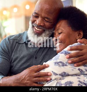 Close Up Of Loving Senior Couple At Home Sitting On Sofa Hugging Stock Photo