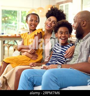 Family At Home Sitting On Sofa Together Streaming Show Or Movie To TV Stock Photo