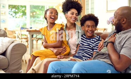 Family Hanging Out At Home Sitting On Sofa Together Talking Together Stock Photo