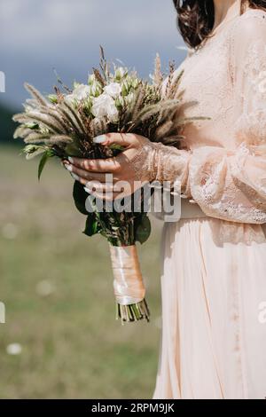 A vertical closeup shot of a bridesmaid in a pink dress holding a bouquet Stock Photo