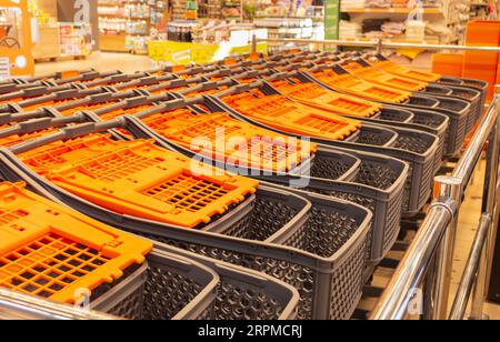 Shopping carts in shopping mall. Marketplace. Stacked shopping carts. Retail place. Shopping trolleys with orange handle. Hypermarket interior. Stock Photo