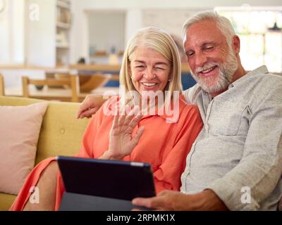 Retired Senior Couple At Home Making Video Call On Digital Tablet Stock Photo