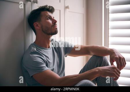 Close Up Of Depressed Man Suffering With Poor Mental Health Sitting On Floor At Home Stock Photo