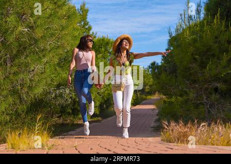 Female friends having fun on vacation in a park in summer walking on a path Stock Photo