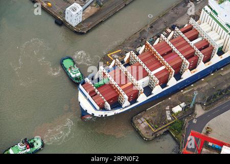 Tug boats guiding a container ship into Seaforth Docks, Liverpool, Merseyside, north west England,UK Stock Photo