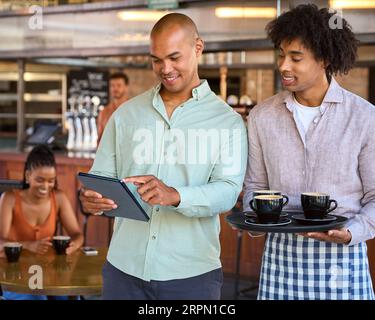 Male Manager With Digital Tablet And Waiter Working In Restaurant Or Coffee Shop Stock Photo
