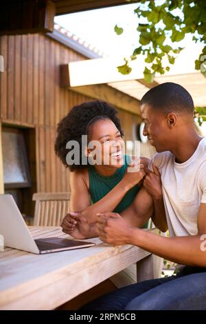 Couple With Laptop Outdoors Sitting At Table At Home Stock Photo