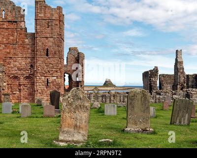View from the grave yard of Lindisfarne church with the abbey runis and the castle on it's rocky perch in the centre background. Stock Photo