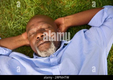 Overhead Shot Of Senior Man Sleeping On Grass Outdoors In Garden At Home Stock Photo