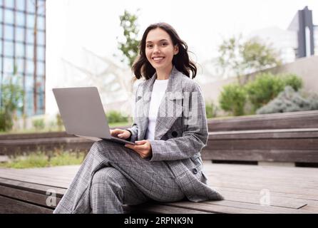 Happy young businesswoman using laptop computer working in urban area Stock Photo