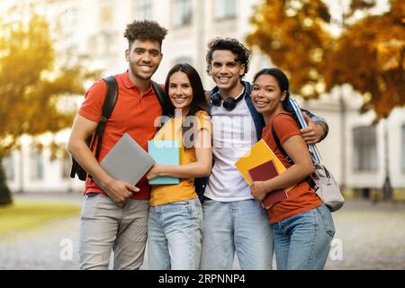 Multiethnic group of cheerful young students standing together outdoors Stock Photo