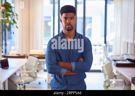 Portrait Of Young Serious Businessman Standing In Modern Office Stock Photo