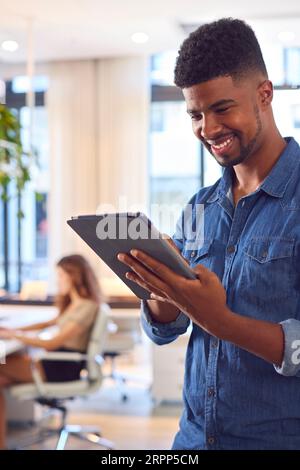 Young Smiling Businessman With Digital Tablet Standing And Working In Modern Office Stock Photo