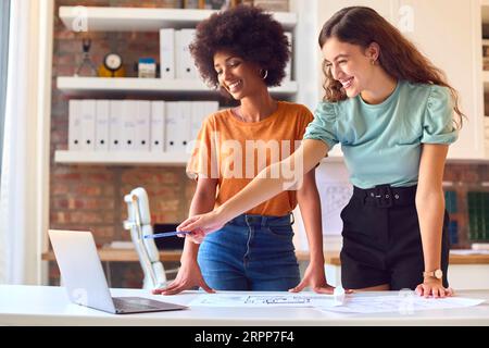 Two Young Female Architects Meeting And Discussing Building Plans In Modern Office Stock Photo