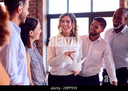 Businesswoman Leading Team Meeting In Busy Multi-Cultural Office Stock Photo