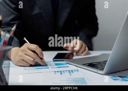 Businessperson reviewing documents with pen, analyzing data on graph report statistic and chart finance, budget, investment, accountant, diagram on de Stock Photo